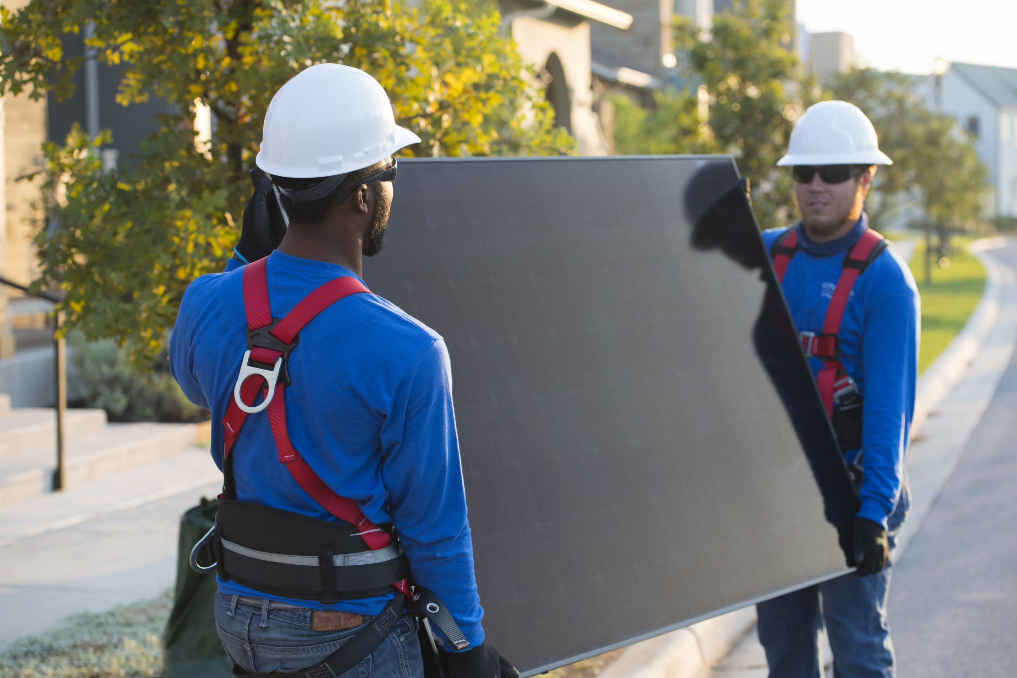2 guys carrying a solar panel for a solar panel installation